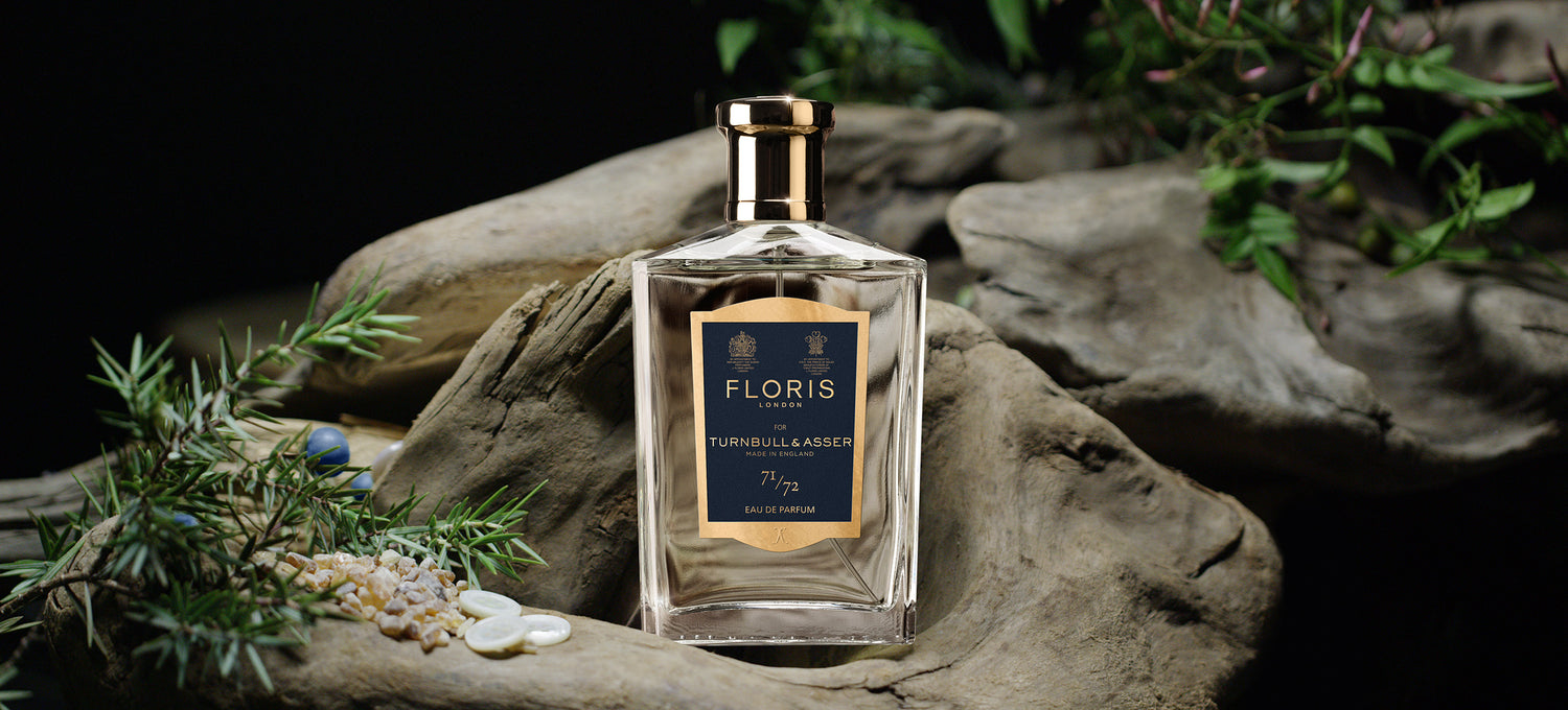 A bottle of 71/72 Eau de Parfum on a stone and green background with Juniper Berries