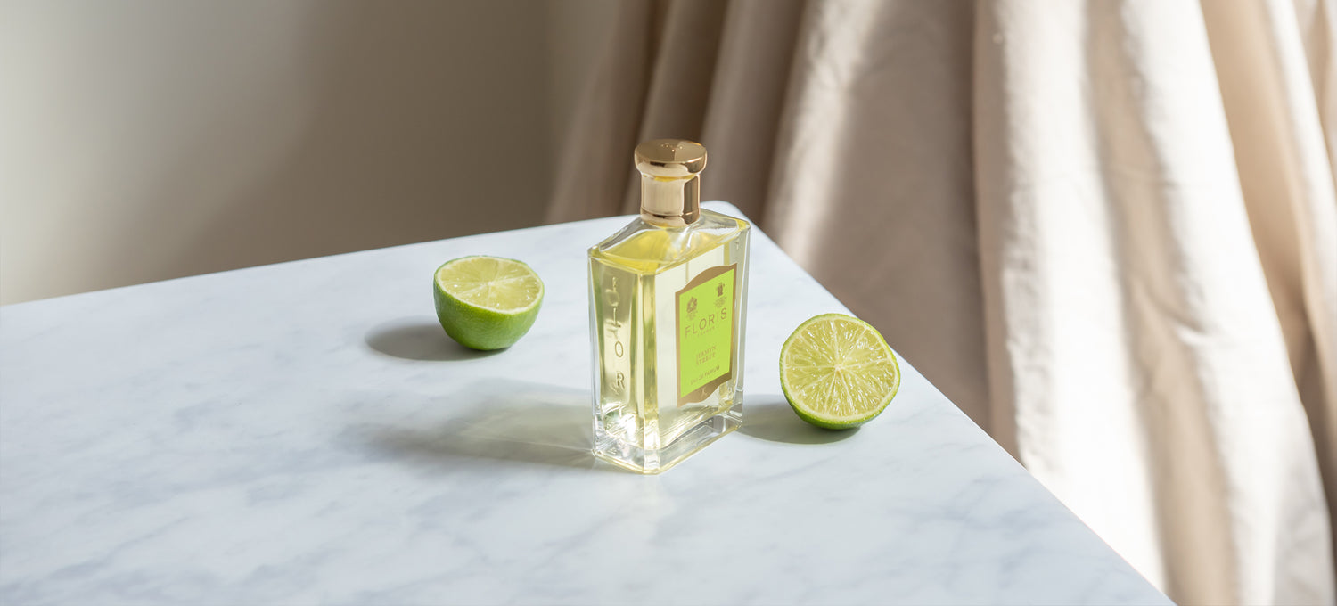 A bottle of Floris London Jermyn Street Eau de Parfum on a marble counter with Limes either side of the bottle