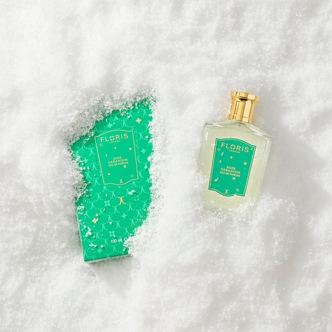 A Floris London UK Rose Geranium | Limited Edition perfume bottle and box partially buried in white snow.