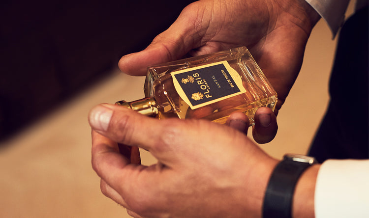 A man holding a bottle of Floris London Santal Eau de Toilette