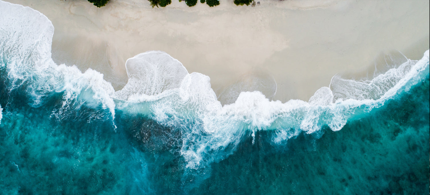 A beach with white and blue waves coming in
