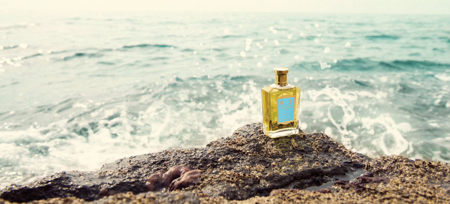 A bottle of Sirena Eau de Parfum on rocks with waves in the background