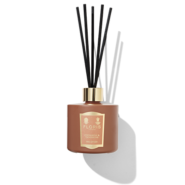 Orange diffuser bottle with reeds coming out of the top