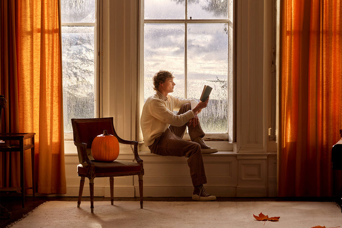 Man sits in front of a window reading a book