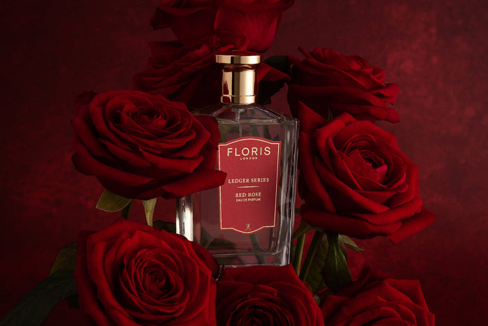 A bottle of Red Rose from Floris London surrounded by red roses, infront of a red background