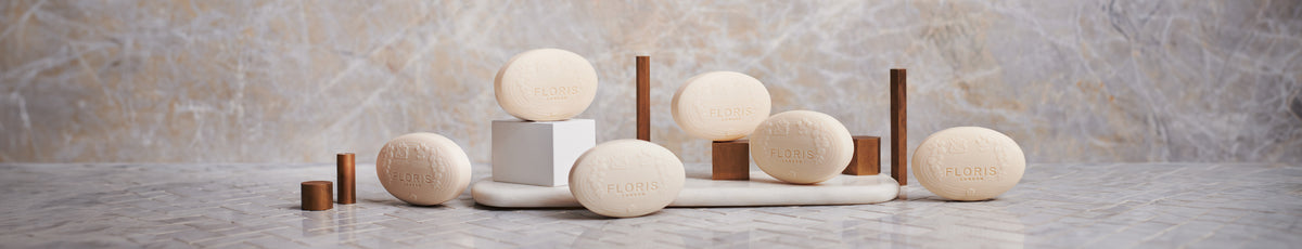 Several Floris brand soaps are displayed on a marble surface with a textured background.