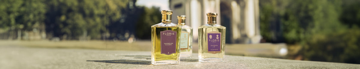 Three Floris perfume bottles on a stone ledge with a blurred outdoor background.