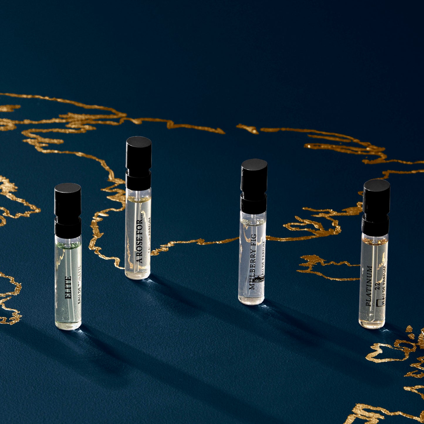 Four Pick Your Own - Sample Set vials by Floris London UK on a dark blue surface with gold line art, expertly crafted in England.