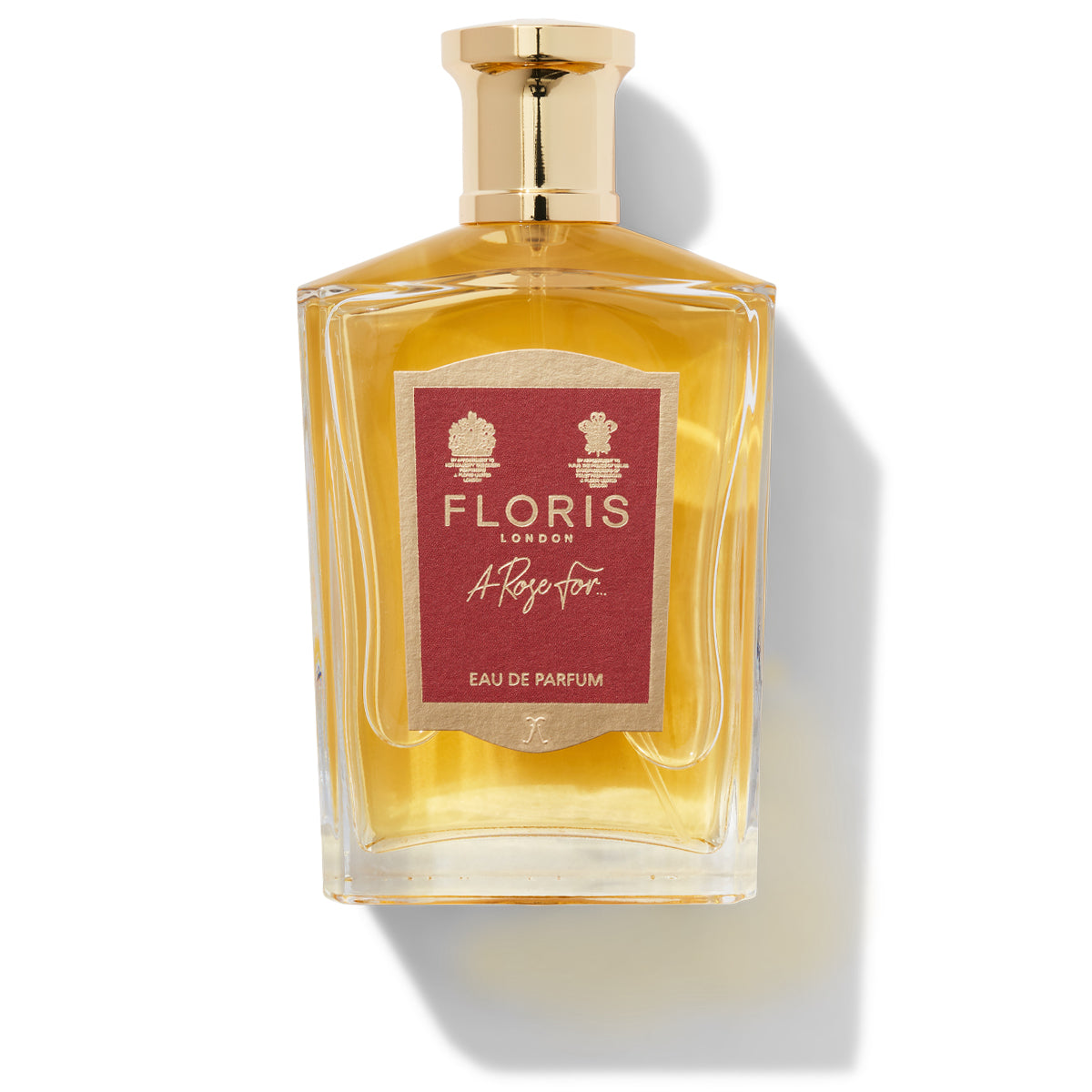 A 100ml bottle of Floris London’s "A Rose For... - Eau de Parfum" featuring a gold cap and a red label, casting a shadow on a pristine white background. This exquisite gift embodies sophistication with its signature scent.