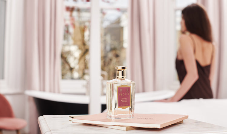 Lady blurred in the background with a bottle of Floris London Cherry Blossom Intense Eau de Parfum 