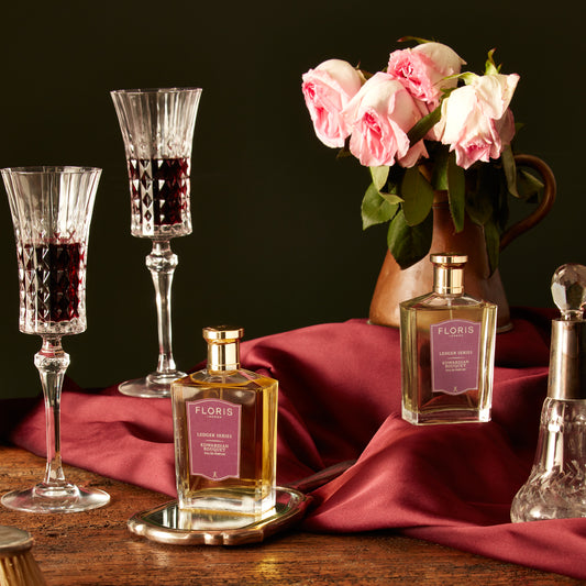 Elegant Edwardian Bouquet by Floris London UK, featuring perfume bottles and roses on a red cloth-covered wooden table, enhanced with a jasmine scent.