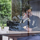 A man in a turtleneck sits at a desk with a typewriter, perfume, and Floris London UK's Elite Moisturiser, gazing thoughtfully out the window.