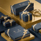 Navy blue Floris London UK Gift Wrap boxes with gold ribbons, displayed on gold and navy platforms.