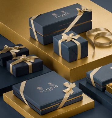 Navy blue Floris London UK Gift Wrap boxes with gold ribbons, displayed on gold and navy platforms.