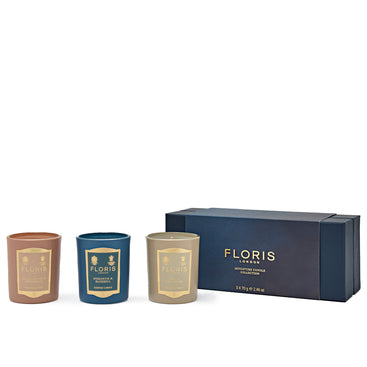 Three beautiful candles from the Floris London Miniature Candle Collection in brown, teal, and ivory rest elegantly beside a blue and gold packaging box.
