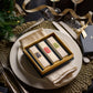 Perched elegantly on a dinner plate and accented by cutlery and festive decor, the Perfumer's Trilogy: For Him by Floris London is a gift box containing three rectangular packages. Perfect for the festive season, this is an ideal gift that embodies British men’s fragrances, adding an aromatic touch to your celebrations.