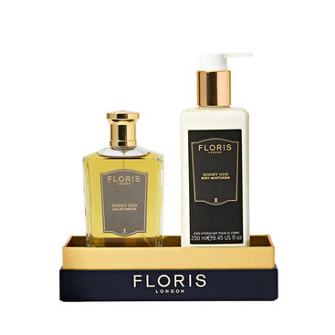 Floris London UK's Sweet Lux | Honey Oud Duo, featuring Eau de Parfum and Body Moisturiser, comes in luxe black and gold packaging on a matching tray.