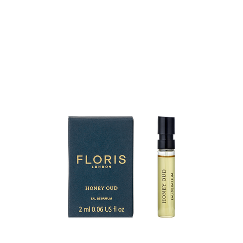 A 2 ml spray vial of Floris London Honey Oud - Eau de Parfum sits beside its black and gold box, both labeled with the brand and fragrance name.