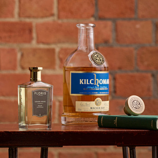 A Floris London UK Islay perfume bottle sits on a table against a brick wall, its scent featuring notes of bergamot.