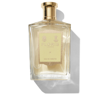 Clear glass bottle with gold spray top and yellow JF label