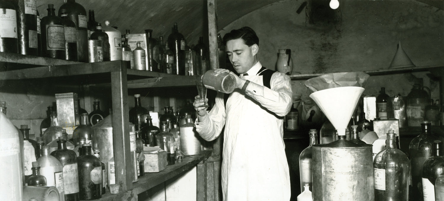 An older image of a Floris family member pouring oils into a bottle 