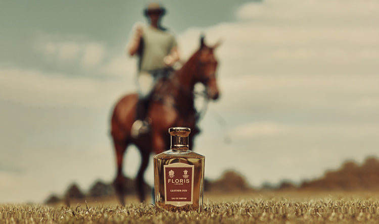 Background showing a horse and rider with a bottle of Floris London Leather Oud in the forefront