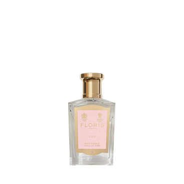 A transparent perfume bottle with a gold cap and pink label reads "Floris London Lily - Bath Essence," offering a delicate lily of the valley floral scent.