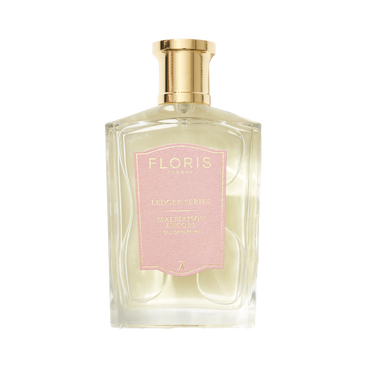 Clear perfume bottle with gold cap and pink label reading "Floris London UK, Malmaison Encore," exuding captivating allure.