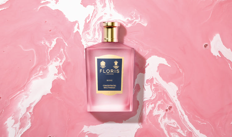 A close up image of Floris London Rose Mouthwash on a Pink swirled background