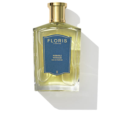 A bottle of Neroli Voyage - Eau de Parfum by Floris London, adorned with a blue label and gold cap, rests on a white background. This exquisite fragrance delivers a refreshing citrus burst with notes of neroli.