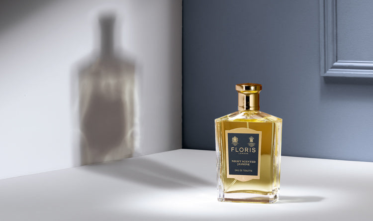 A bottle of Floris London Night Scented Jasmine with a shadow on the wall behind the bottle