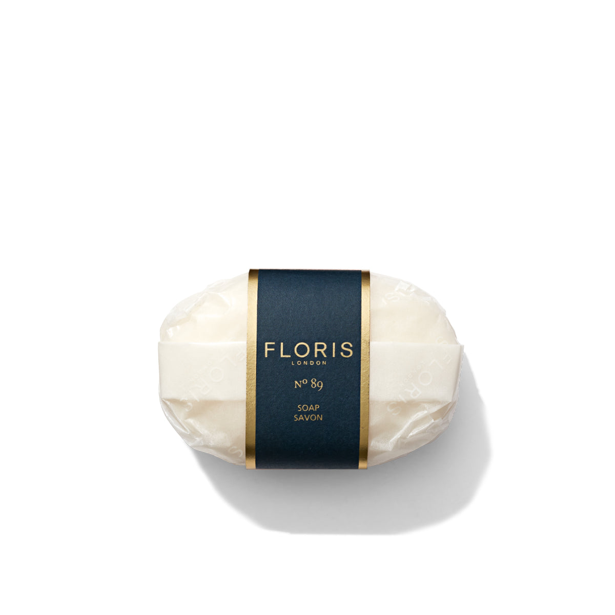 A bar of finely milled No. 89 Soap by Floris London, wrapped in white paper and adorned with a black label featuring gold accents, set against a white background.