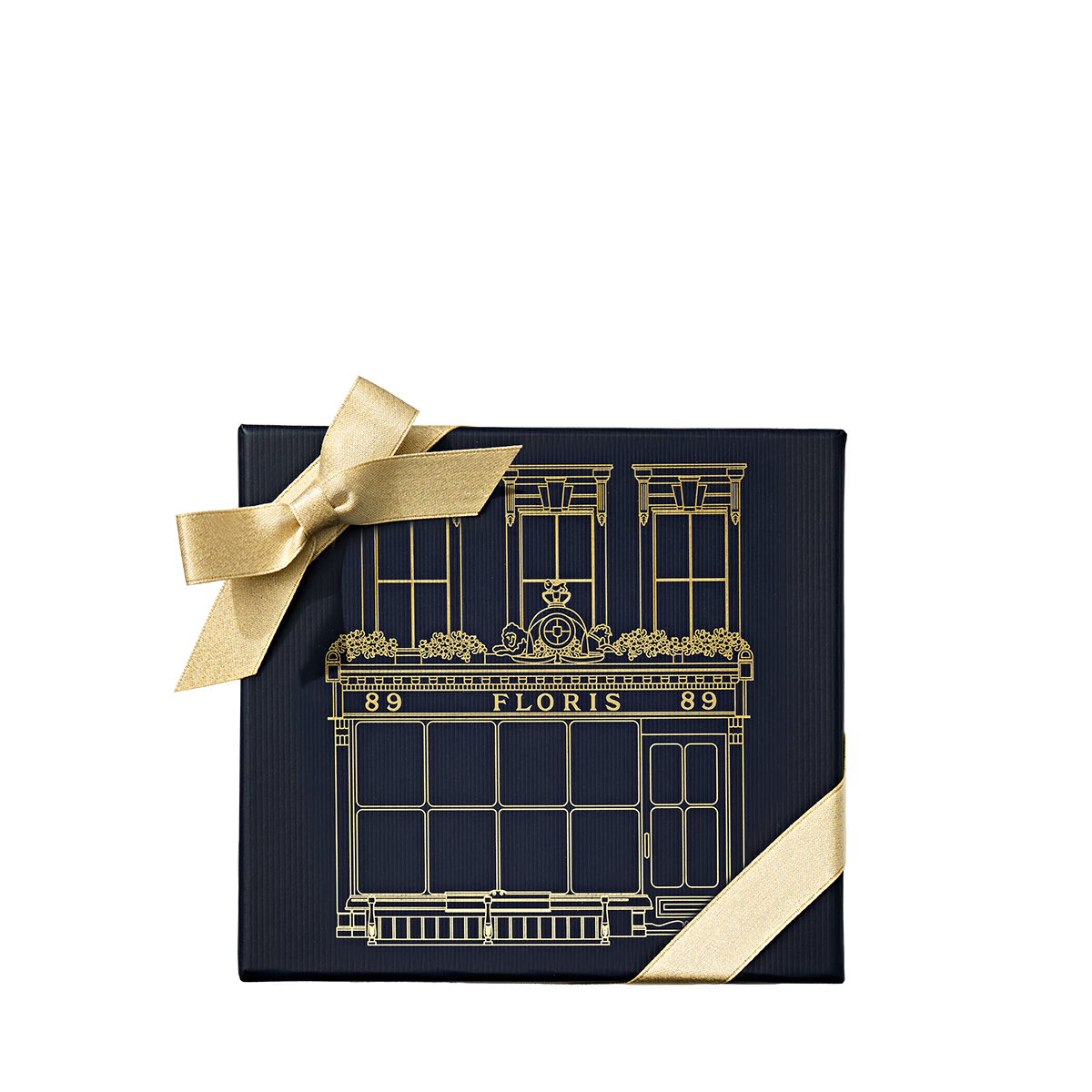 A square, dark blue Perfumer’s Trilogy: For Her gift box decorated with a gold line drawing of a storefront and tied with a gold ribbon.