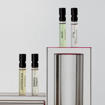 Four Floris London UK "Pick Your Own - Sample Box" mini perfumes, each labeled, are crafted in England and displayed on metallic and white stands.