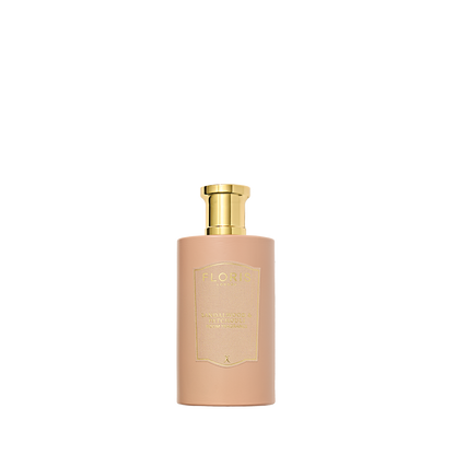 A beige Floris London Sandalwood & Patchouli bottle with a golden cap sits elegantly against a white backdrop, exuding rose and sandalwood hints.