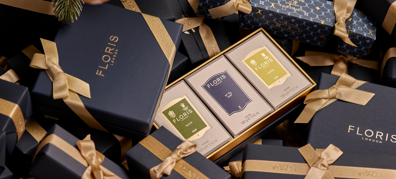 A boxed Soap Collection For Him from Floris London, featuring three exquisite soap products, nestled in-between beautifully gift wrapped presents. This luxurious gift set is perfect for the holiday season.