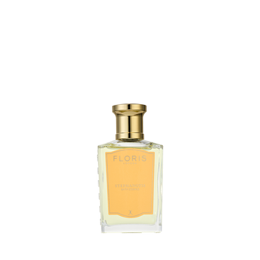 A clear glass bottle with a gold cap, labeled “Floris London Stephanotis Bath Essence,” evokes delicate notes of orange blossom.